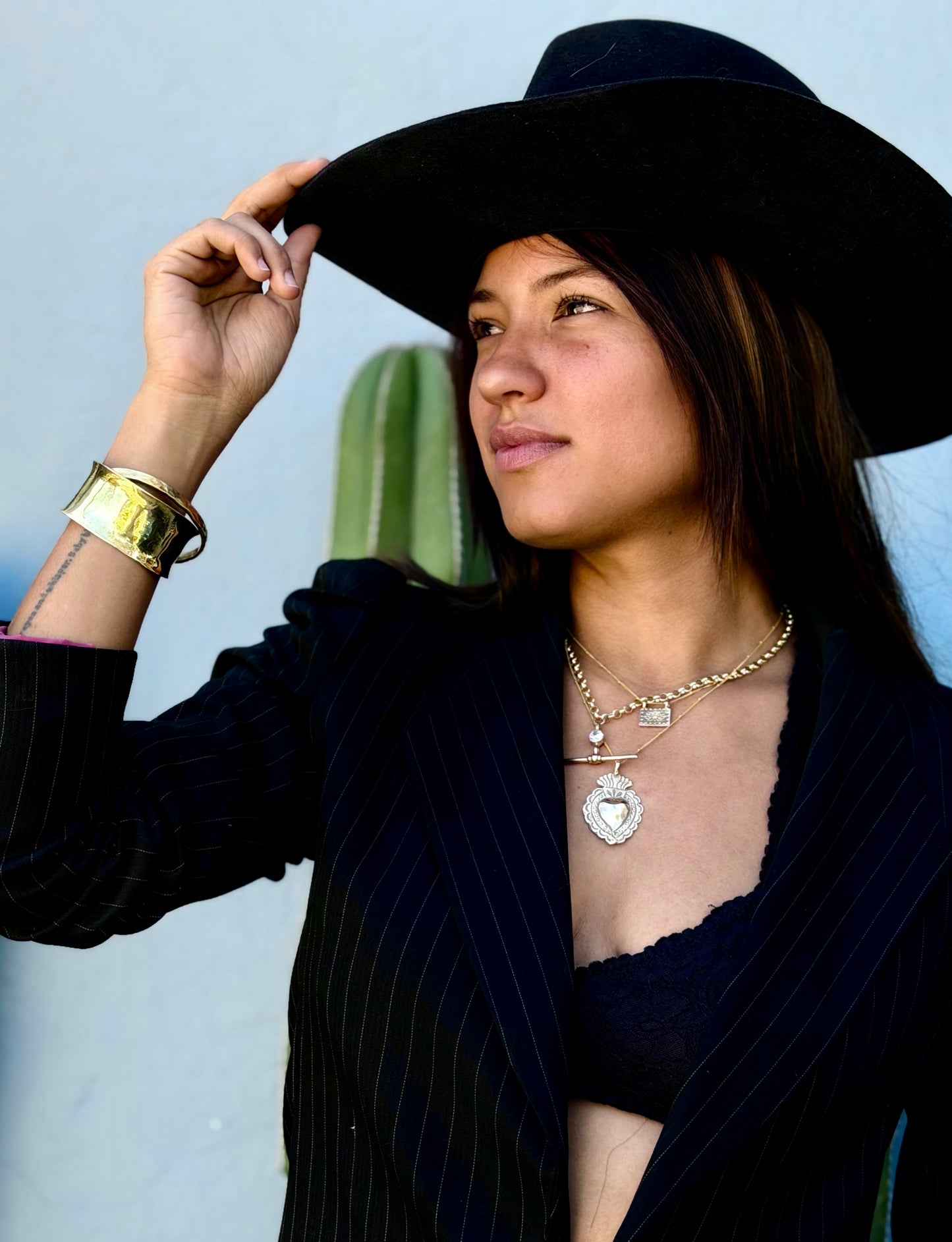 Woman dressed in black wearing a stunning gold cuff and layering necklaces.