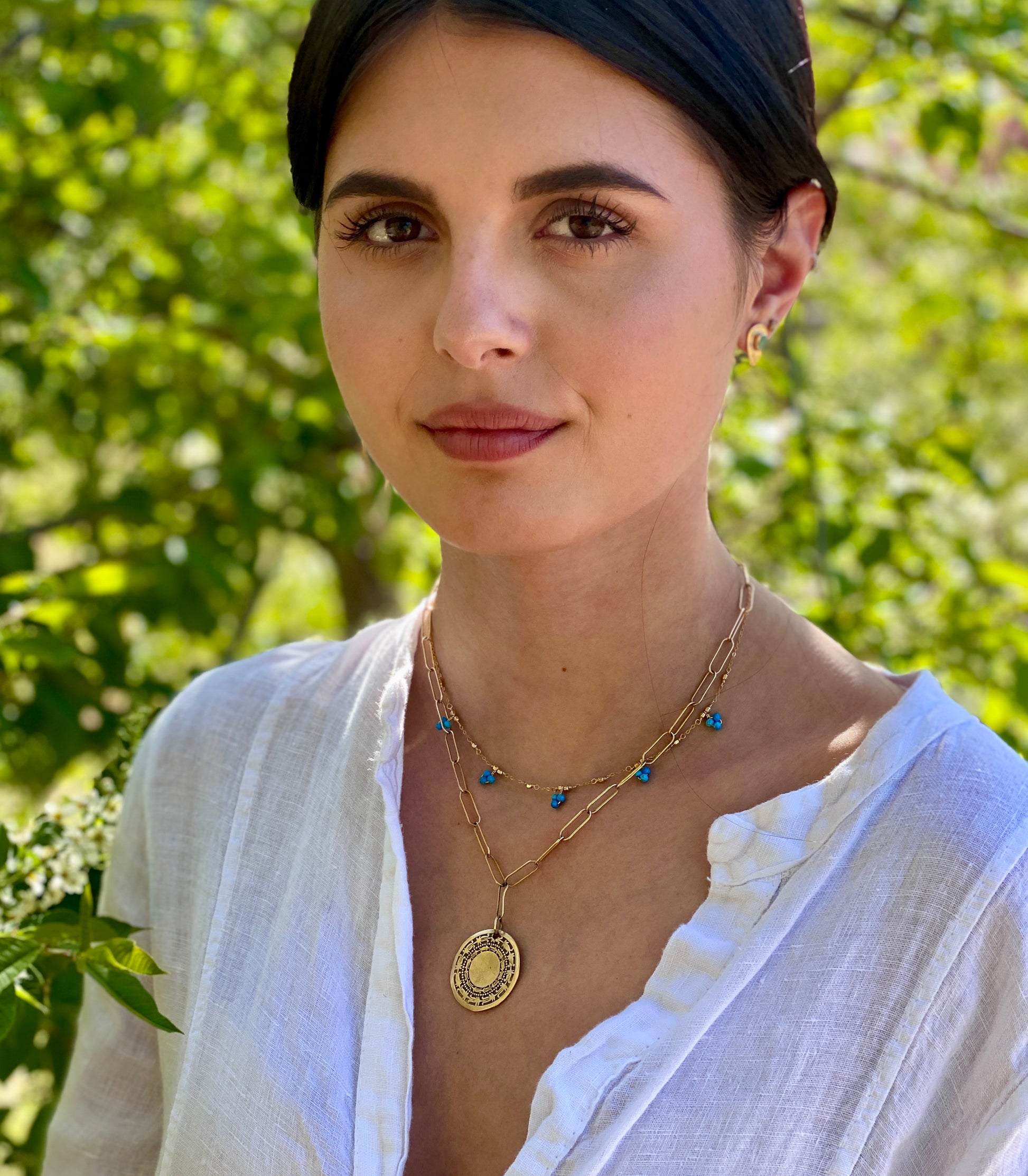 Model wearing African Coin Necklace in gold layered with other boho gold jewelry
