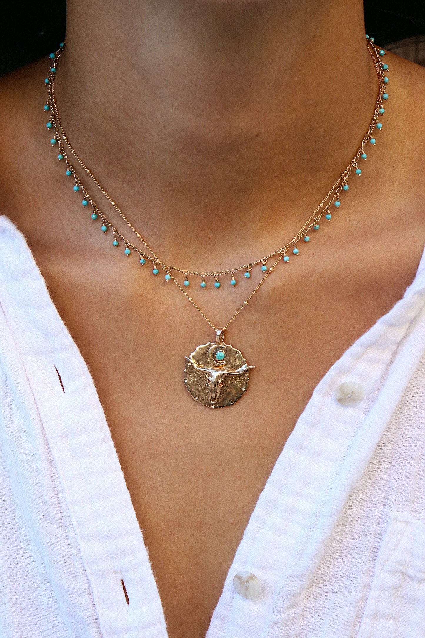 Bronze pendant engraved with longhorn bullhead and turquoise sun on model