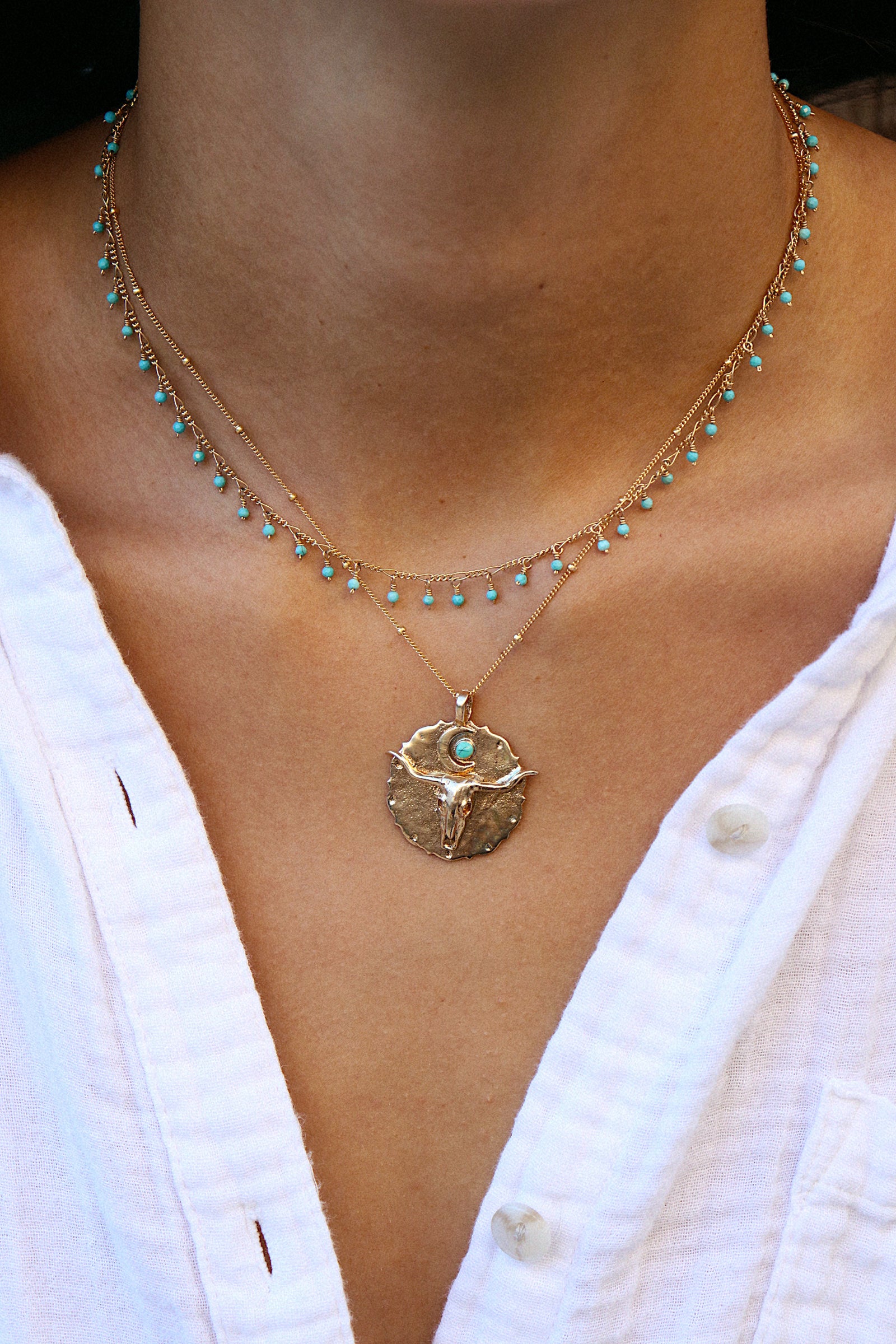 Bronze pendant engraved with longhorn bullhead and turquoise sun on model