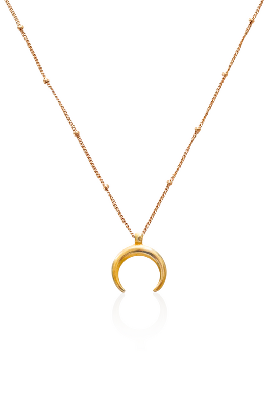 Close-up of gold moon pendant hanging downward