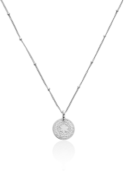 Close-up of silver coin pendant featuring sun and moon symbols