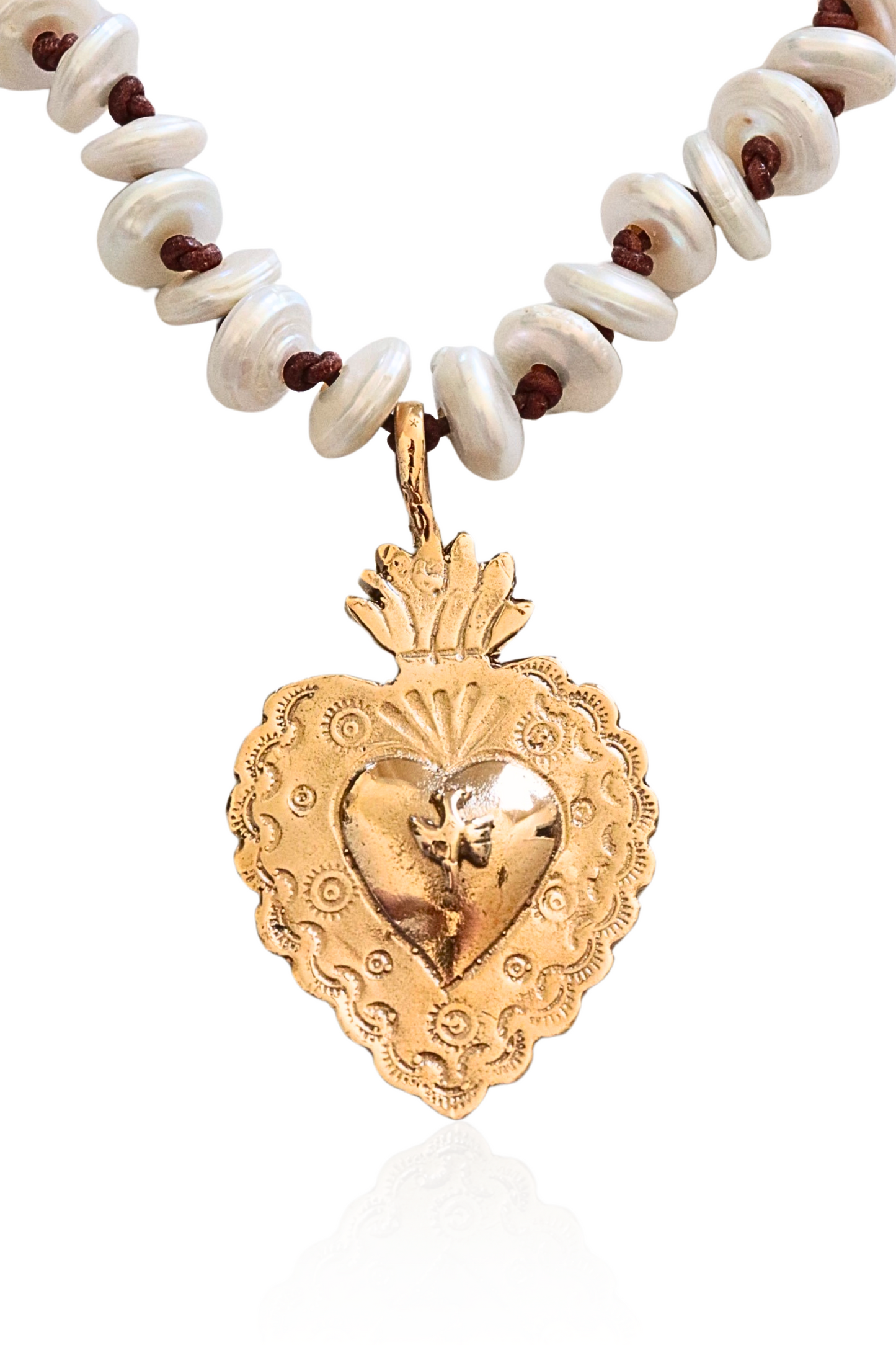Close-up of bronze Sacred Heart on pearl and leather strand