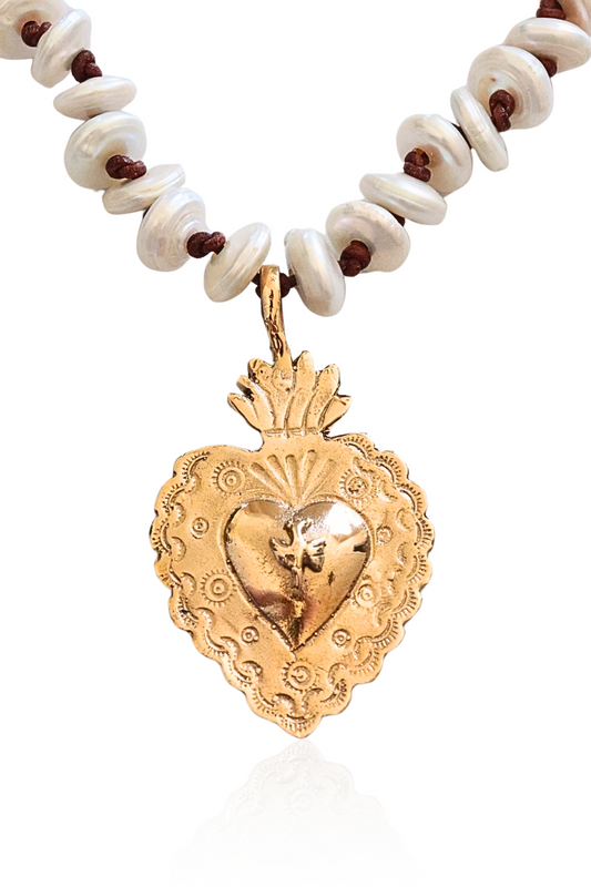Close-up of bronze Sacred Heart on pearl and leather strand