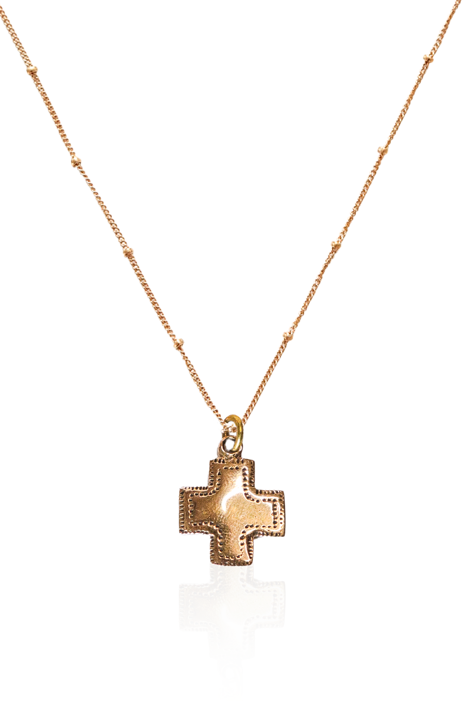 Close-up of engraved bronze cross pendant on gold chain