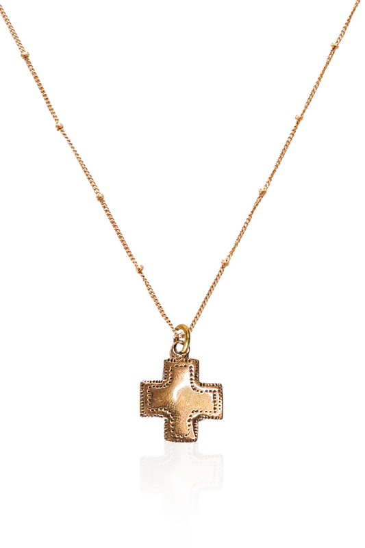 Close-up of engraved bronze cross pendant on gold chain