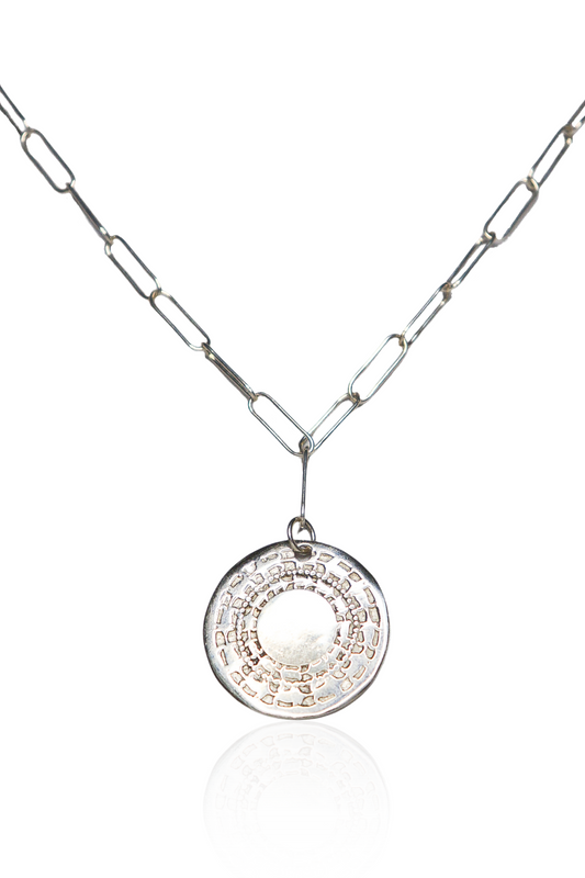 Close-up of silver engraved coin necklace