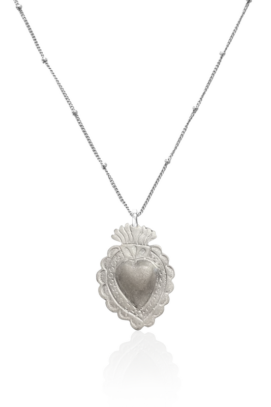 Close-up of silver sacred heart pendant on chain