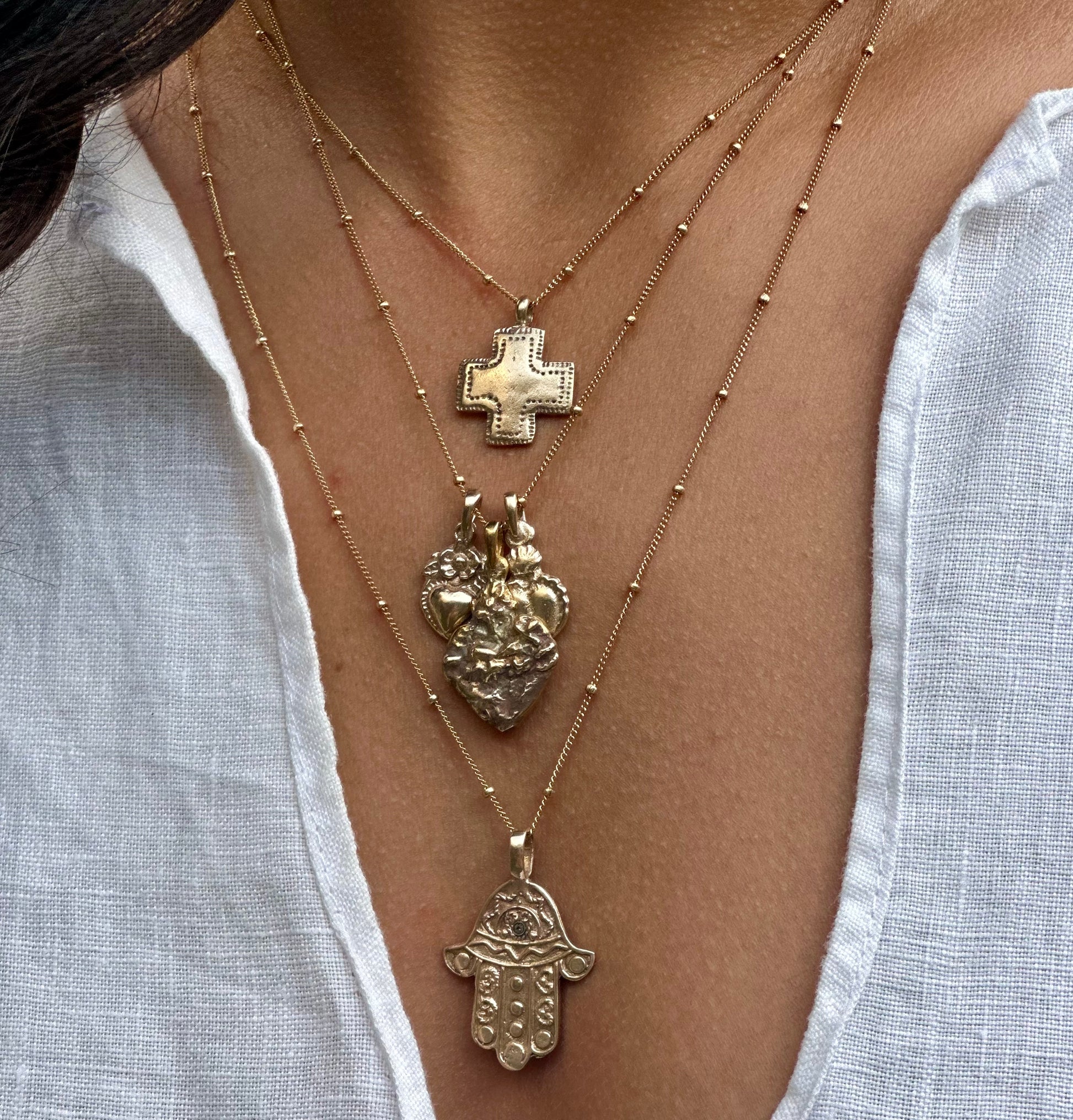 Model wearing gold Southwest Cross Necklace layered with other pieces