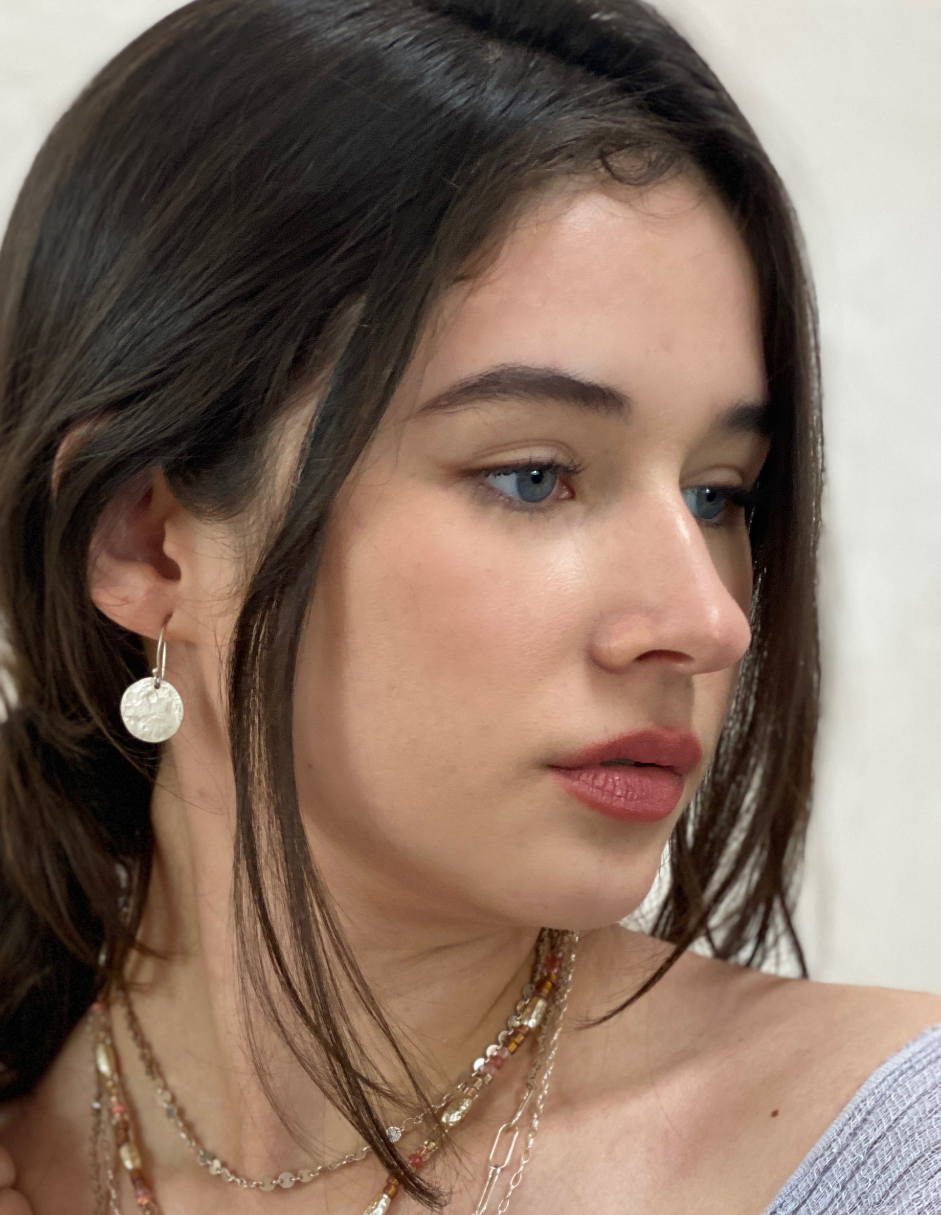 Silver medallion earrings styled on model